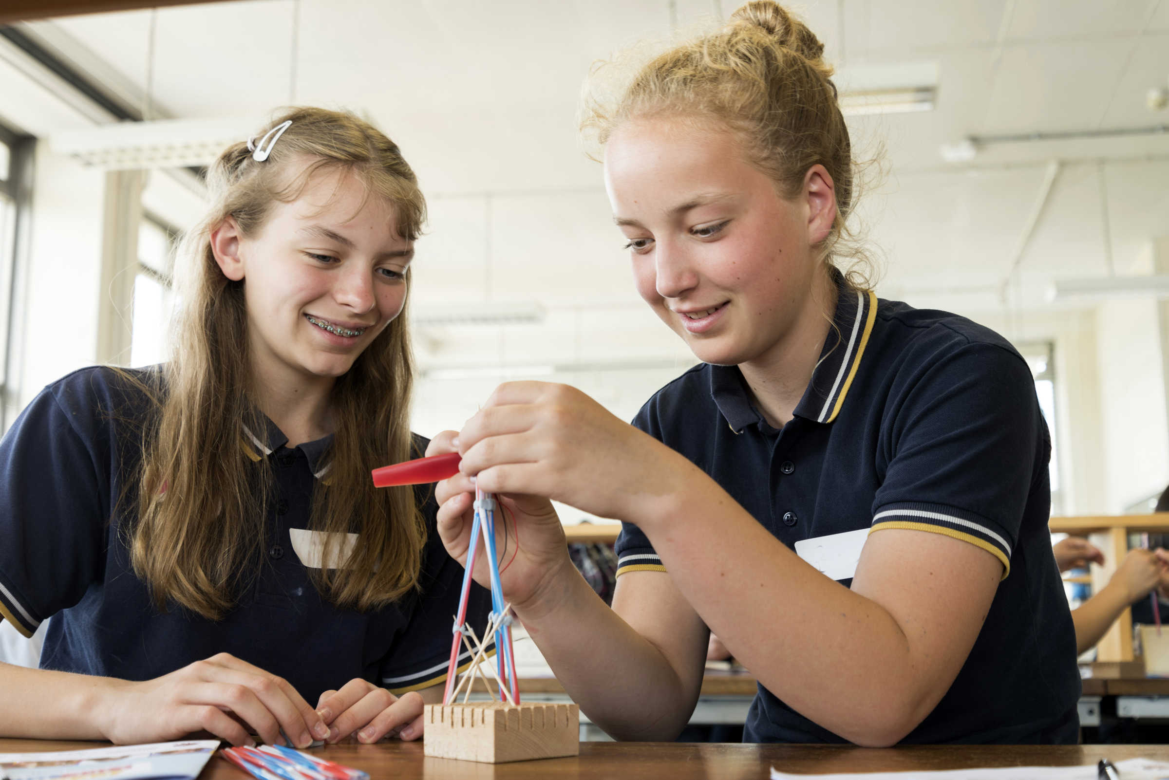 Two girls building a small tower shape project.